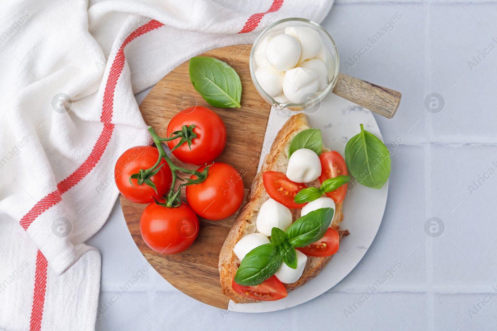 Tasty sandwich with mozzarella cheese, tomatoes and basil on light tiled table, top view Photo of Tasty sandwich with mozzarella cheese, tomatoes and basil on light tiled table, top view