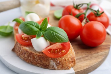 Photo of Tasty sandwich with mozzarella cheese, tomatoes and basil on light table, closeup