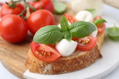 Photo of Tasty sandwich with mozzarella cheese, tomatoes and basil on light table, closeup