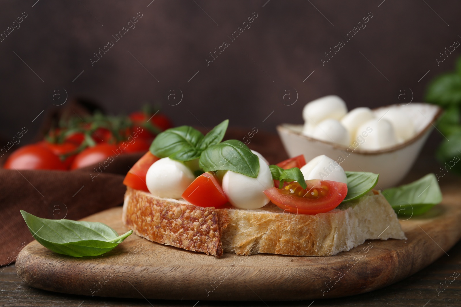 Tasty sandwich with mozzarella cheese, tomatoes and basil on wooden table against brown background, closeup Photo of Tasty sandwich with mozzarella cheese, tomatoes and basil on wooden table against brown background, closeup