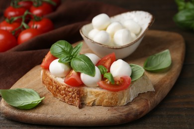 Photo of Tasty sandwich with mozzarella cheese, tomatoes and basil on wooden table, closeup