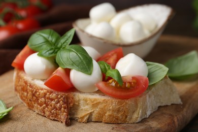 Photo of Tasty sandwich with mozzarella cheese, tomatoes and basil on table, closeup