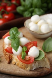 Photo of Tasty sandwich with mozzarella cheese, tomatoes and basil on wooden table, closeup