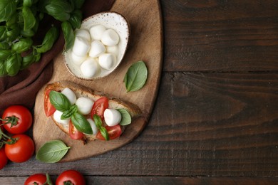 Photo of Tasty sandwich with mozzarella cheese, tomatoes and basil on wooden table, flat lay. Space for text