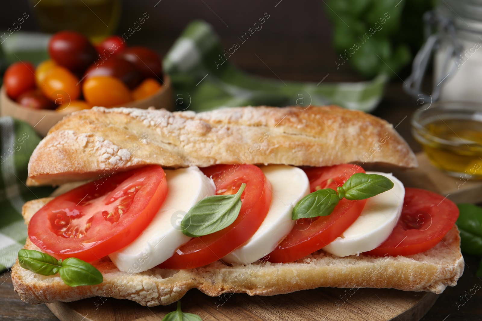 Tasty sandwich with mozzarella cheese, tomatoes and basil on wooden table, closeup Photo of Tasty sandwich with mozzarella cheese, tomatoes and basil on wooden table, closeup