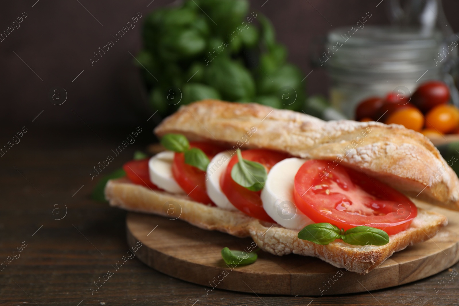 Tasty sandwich with mozzarella cheese, tomatoes and basil on wooden table against brown background, closeup Photo of Tasty sandwich with mozzarella cheese, tomatoes and basil on wooden table against brown background, closeup