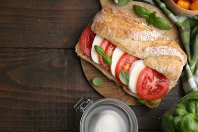 Photo of Tasty sandwich with mozzarella cheese, tomatoes and basil on wooden table, flat lay. Space for text