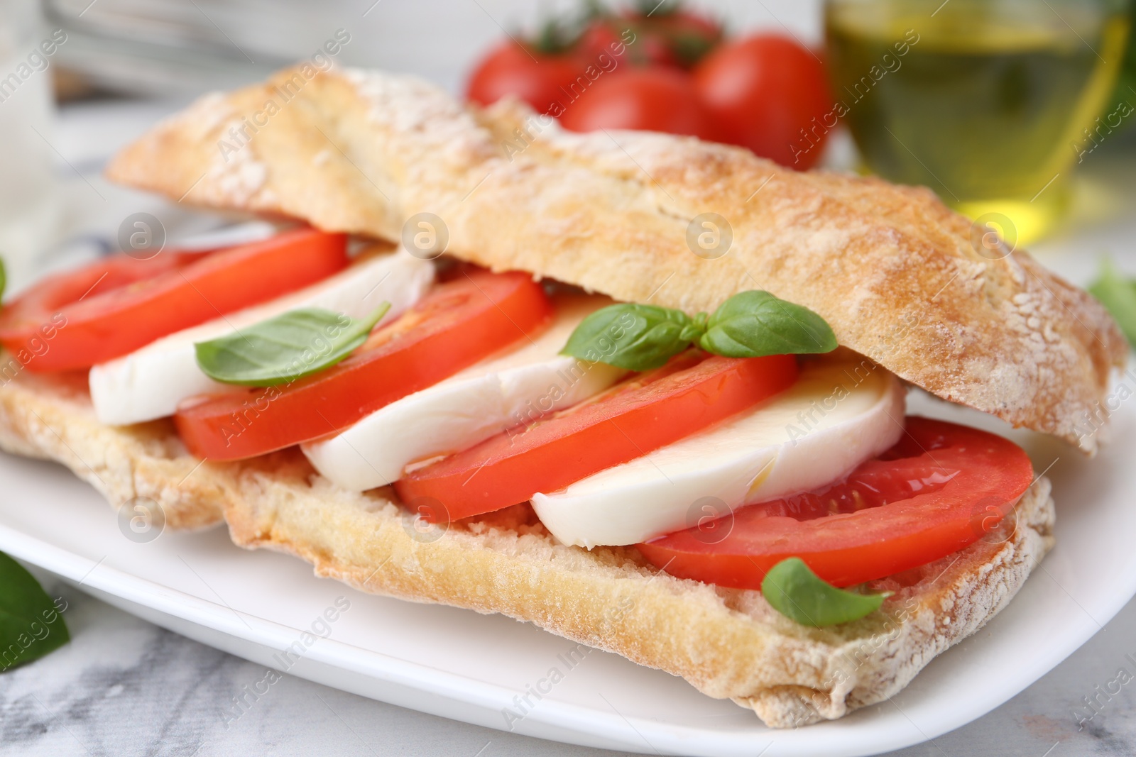 Tasty sandwich with mozzarella cheese, tomatoes and basil on white marble table, closeup Photo of Tasty sandwich with mozzarella cheese, tomatoes and basil on white marble table, closeup