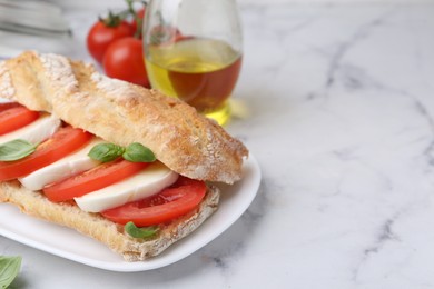 Photo of Tasty sandwich with mozzarella cheese, tomatoes and basil on white marble table, closeup. Space for text