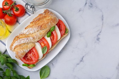 Photo of Tasty sandwich with mozzarella cheese, tomatoes and basil on white marble table, flat lay. Space for text