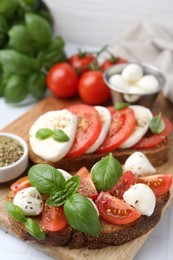 Photo of Tasty sandwiches with mozzarella cheese, tomatoes, basil and spices on light table, closeup
