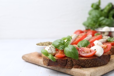 Photo of Tasty sandwiches with mozzarella cheese, tomatoes, basil and spices on light tiled table, closeup. Space for text