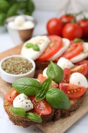 Photo of Tasty sandwiches with mozzarella cheese, tomatoes, basil and spices on light table, closeup