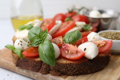 Photo of Tasty sandwiches with mozzarella cheese, tomatoes, basil and spices on light table, closeup