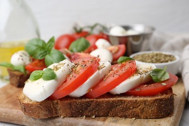 Photo of Tasty sandwiches with mozzarella cheese, tomatoes, basil and spices on light table, closeup