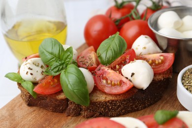 Photo of Tasty sandwiches with mozzarella cheese, tomatoes, basil and spices on light table, closeup