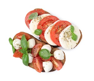 Photo of Tasty sandwiches with mozzarella cheese, tomatoes, basil and spices isolated on white, top view