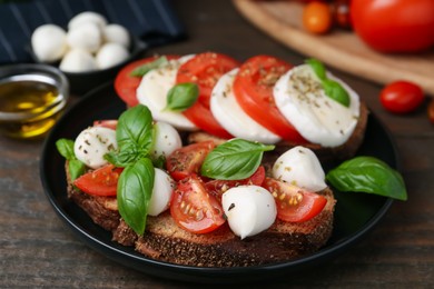 Photo of Tasty sandwiches with mozzarella cheese, tomatoes, basil and spices on wooden table, closeup