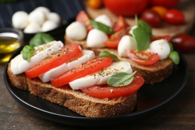 Photo of Tasty sandwiches with mozzarella cheese, tomatoes, basil and spices on wooden table, closeup