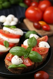 Photo of Tasty sandwiches with mozzarella cheese, tomatoes, basil and spices on wooden table, closeup