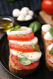 Photo of Tasty sandwiches with mozzarella cheese, tomatoes, basil and spices on wooden table, closeup