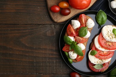 Photo of Tasty sandwiches with mozzarella cheese, tomatoes, basil and spices on wooden table, flat lay. Space for text