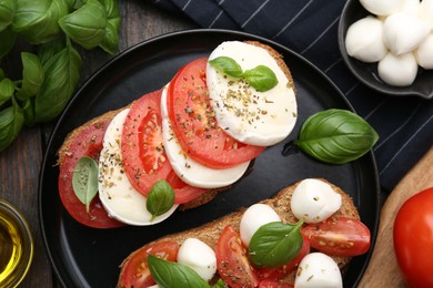 Photo of Tasty sandwiches with mozzarella cheese, tomatoes, basil and spices on wooden table, flat lay