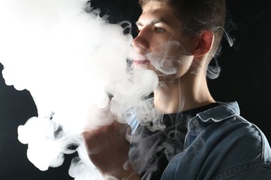 Photo of Man using electronic smoking device on black background