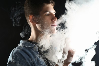Photo of Man using electronic smoking device on black background