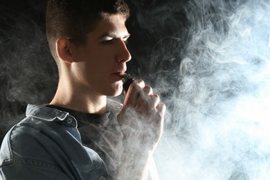 Photo of Man using electronic smoking device on black background