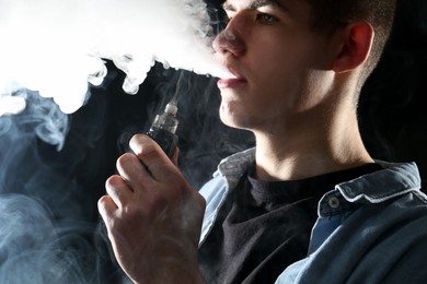 Photo of Man using electronic smoking device on black background
