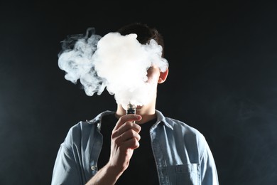 Photo of Man using electronic smoking device on black background