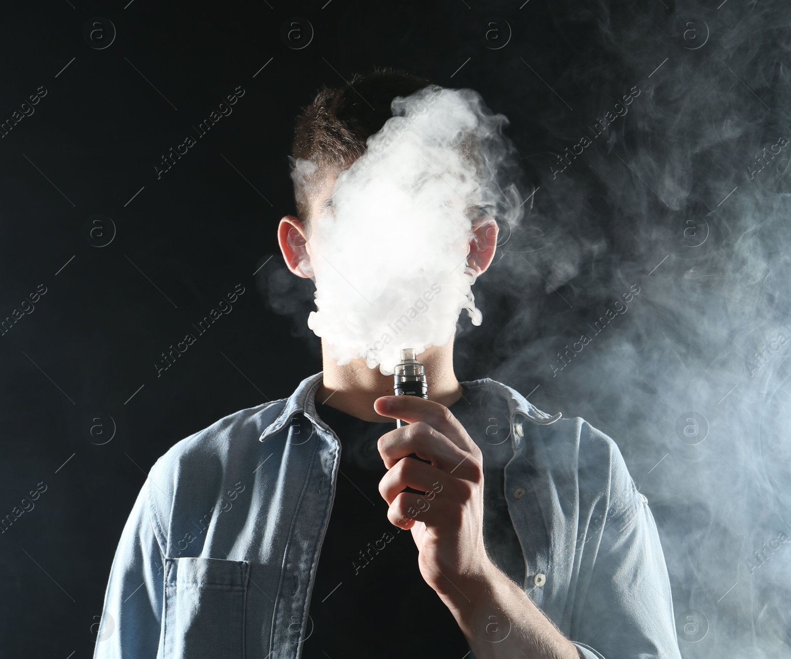 Man using electronic smoking device on black background Photo of Man using electronic smoking device on black background