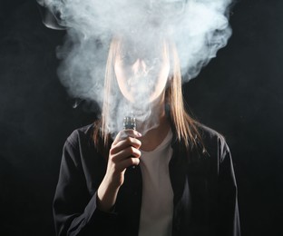 Photo of Woman using electronic smoking device on black background