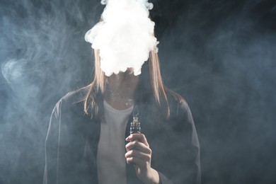 Photo of Woman using electronic smoking device on dark background