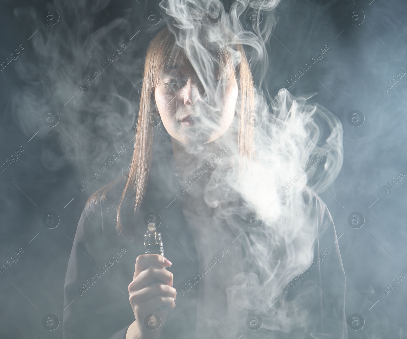 Woman using electronic smoking device on dark background Photo of Woman using electronic smoking device on dark background