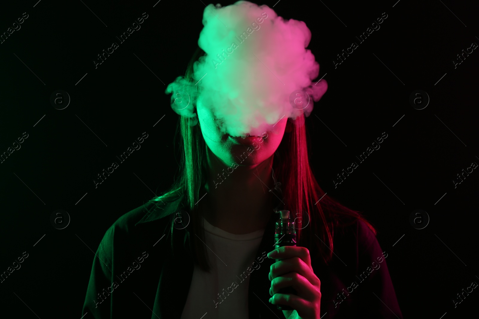 Woman using electronic smoking device in neon lights on black background Photo of Woman using electronic smoking device in neon lights on black background