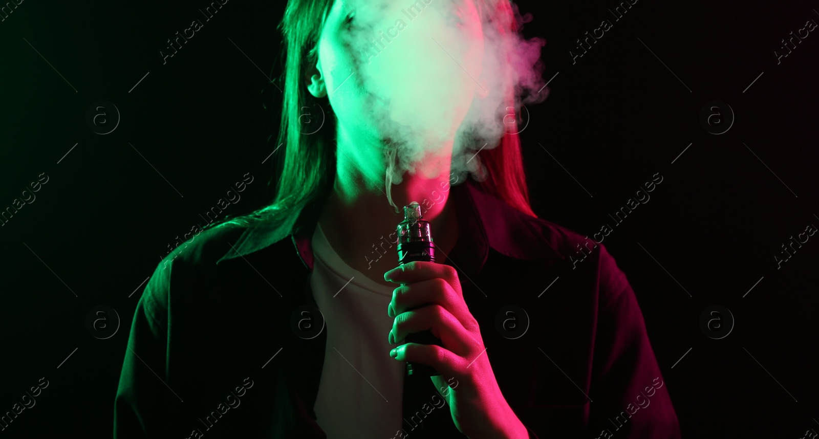 Woman using electronic smoking device in neon lights on black background Photo of Woman using electronic smoking device in neon lights on black background