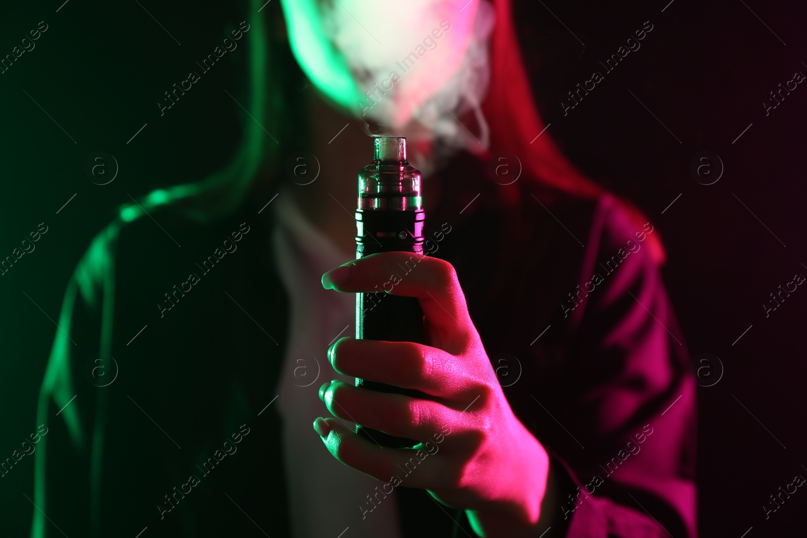 Woman using electronic smoking device in neon lights on black background, closeup Photo of Woman using electronic smoking device in neon lights on black background, closeup