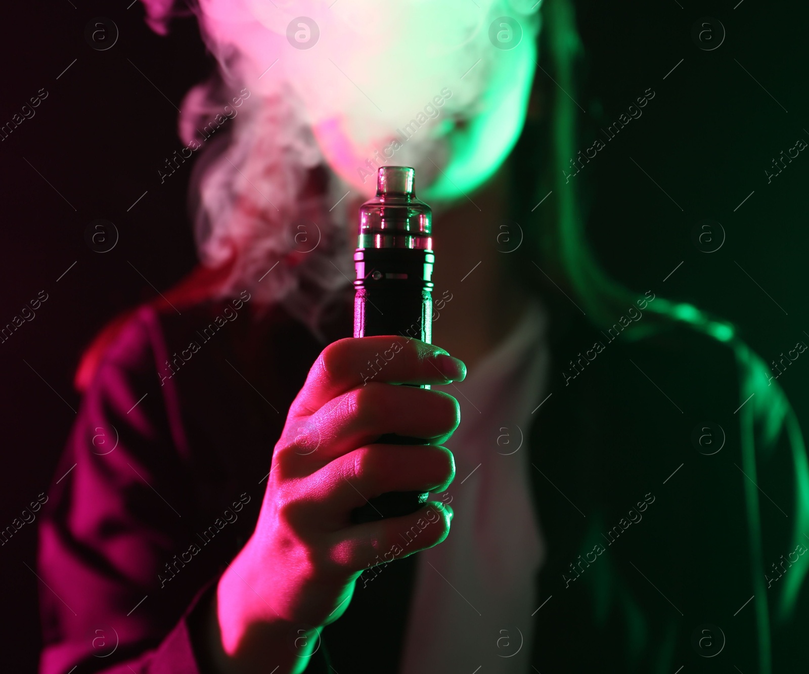 Woman using electronic smoking device in neon lights on black background, closeup Photo of Woman using electronic smoking device in neon lights on black background, closeup