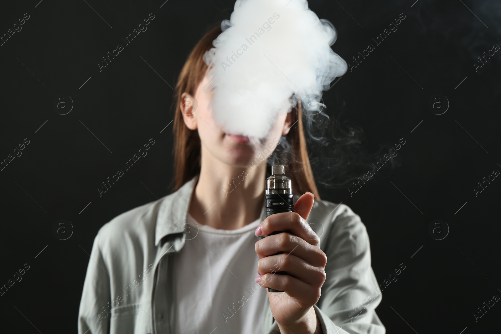 Woman using electronic smoking device on black background Photo of Woman using electronic smoking device on black background