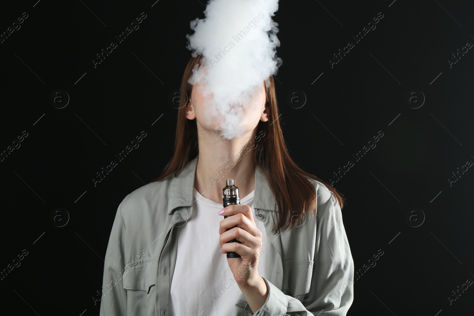 Woman using electronic smoking device on black background Photo of Woman using electronic smoking device on black background