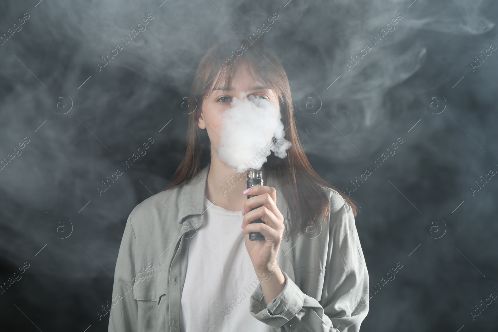 Photo of Woman using electronic smoking device on dark background