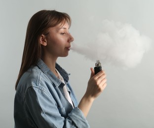 Photo of Woman using electronic smoking device on light grey background