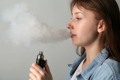 Photo of Woman using electronic smoking device on light grey background
