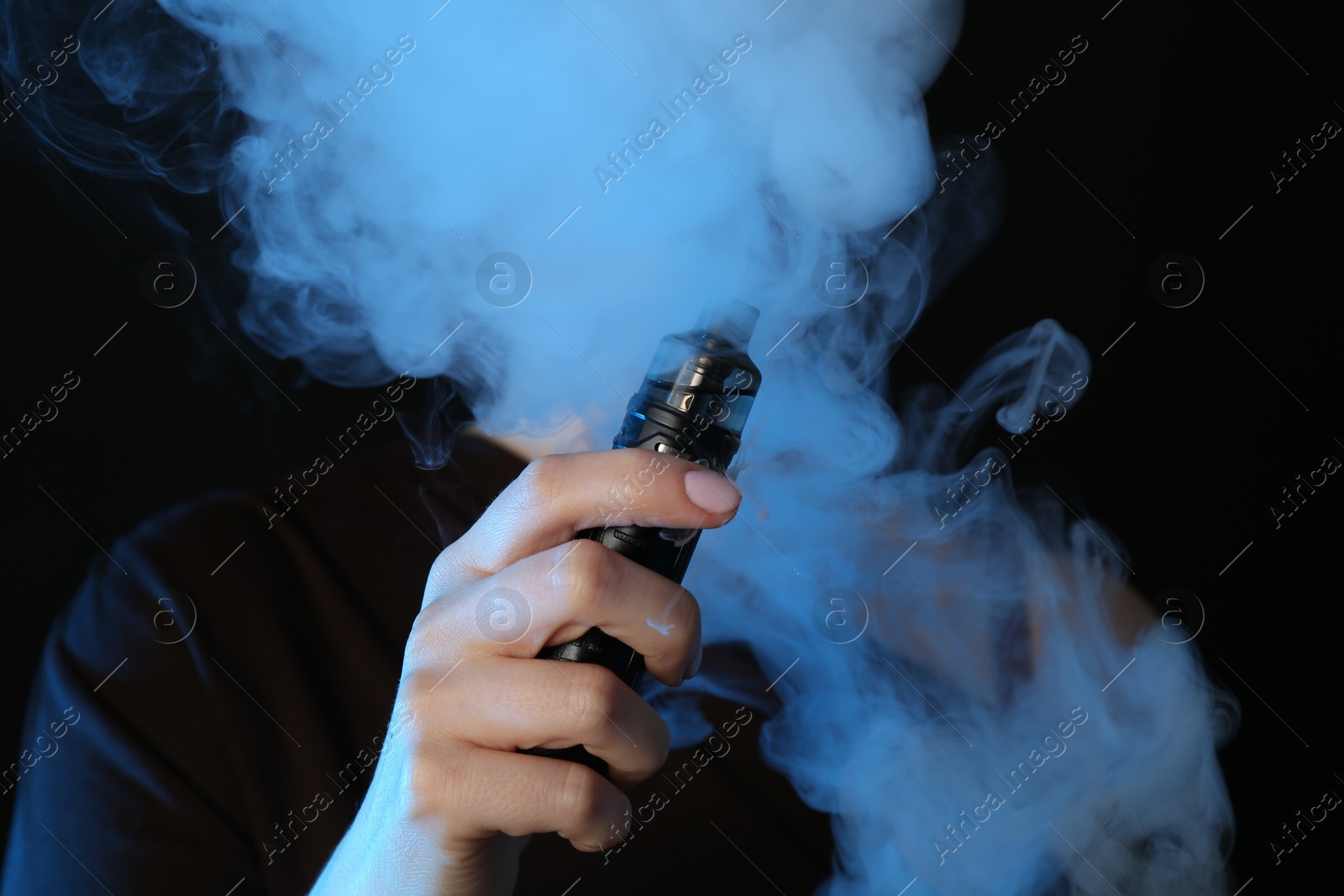 Woman using electronic smoking device in neon lights on black background Photo of Woman using electronic smoking device in neon lights on black background