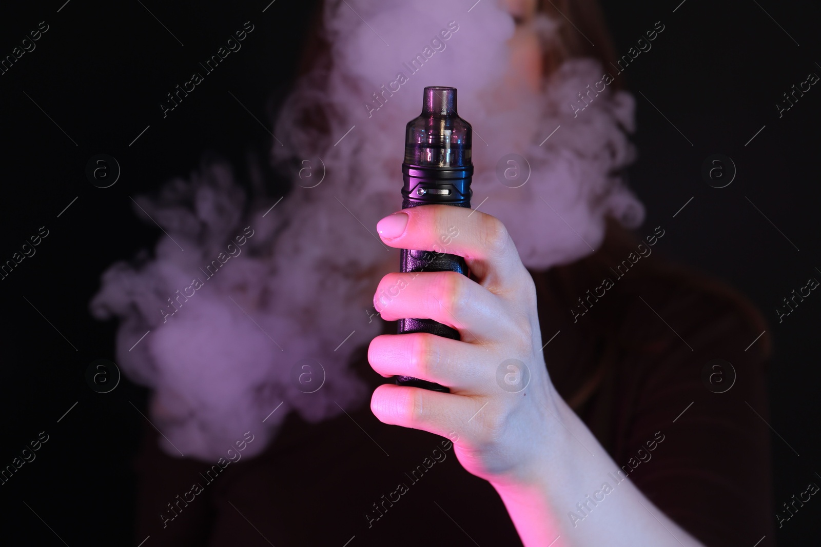 Woman using electronic smoking device in neon lights on black background, closeup Photo of Woman using electronic smoking device in neon lights on black background, closeup