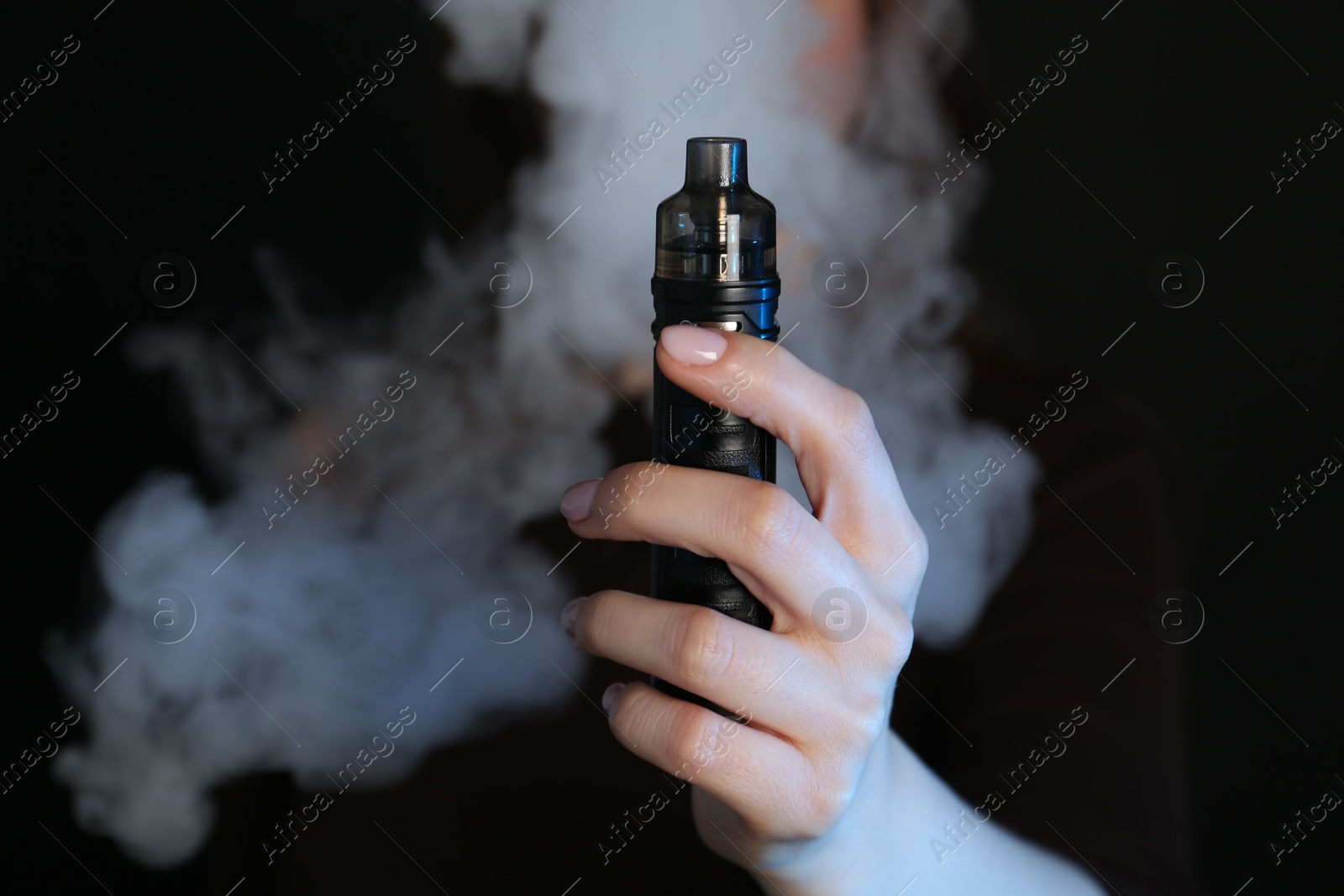 Woman using electronic smoking device on black background, closeup Photo of Woman using electronic smoking device on black background, closeup