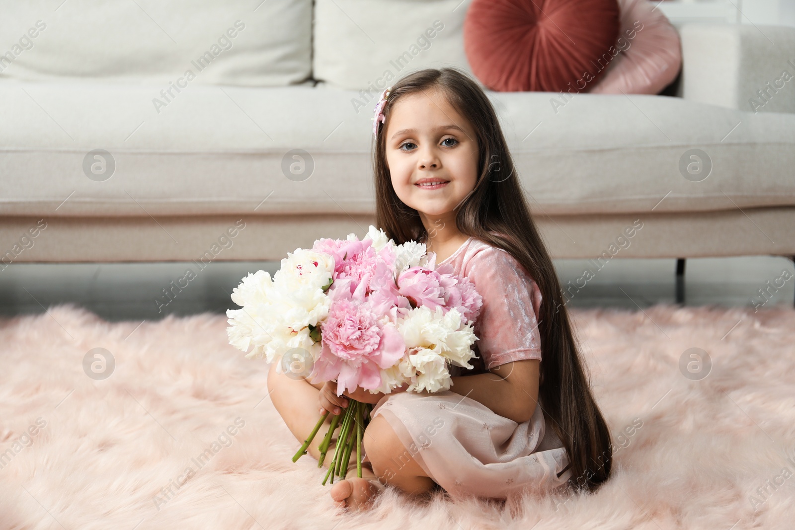 Cute little girl with bouquet of beautiful peonies on floor at home Photo of Cute little girl with bouquet of beautiful peonies on floor at home