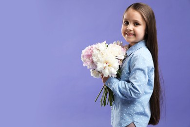 Photo of Cute little girl with bouquet of beautiful peonies on purple background, space for text